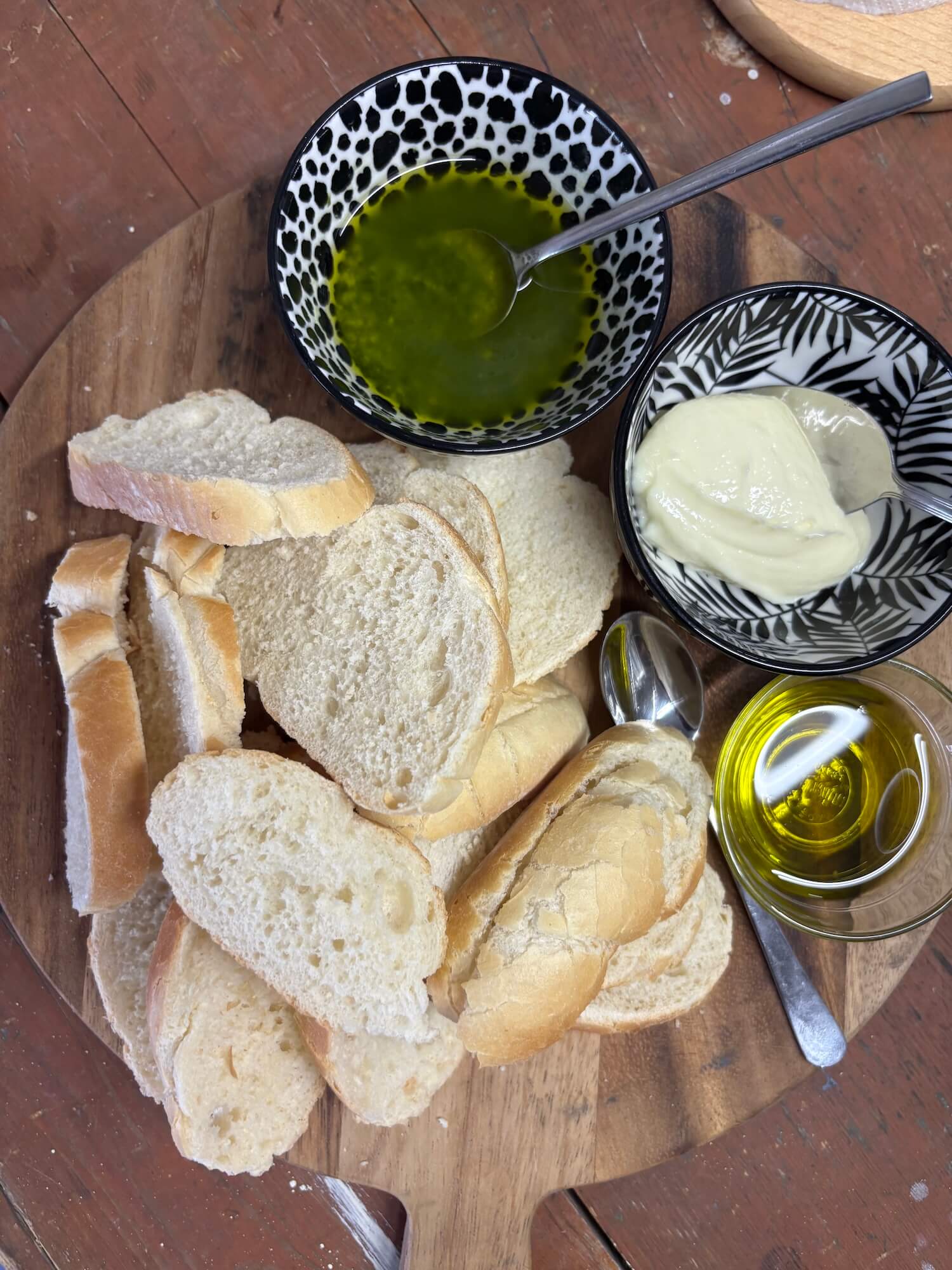 Gezonde ontbijt setup met vers brood, boter, pesto/kruidenspread op houten bord met olijfolie